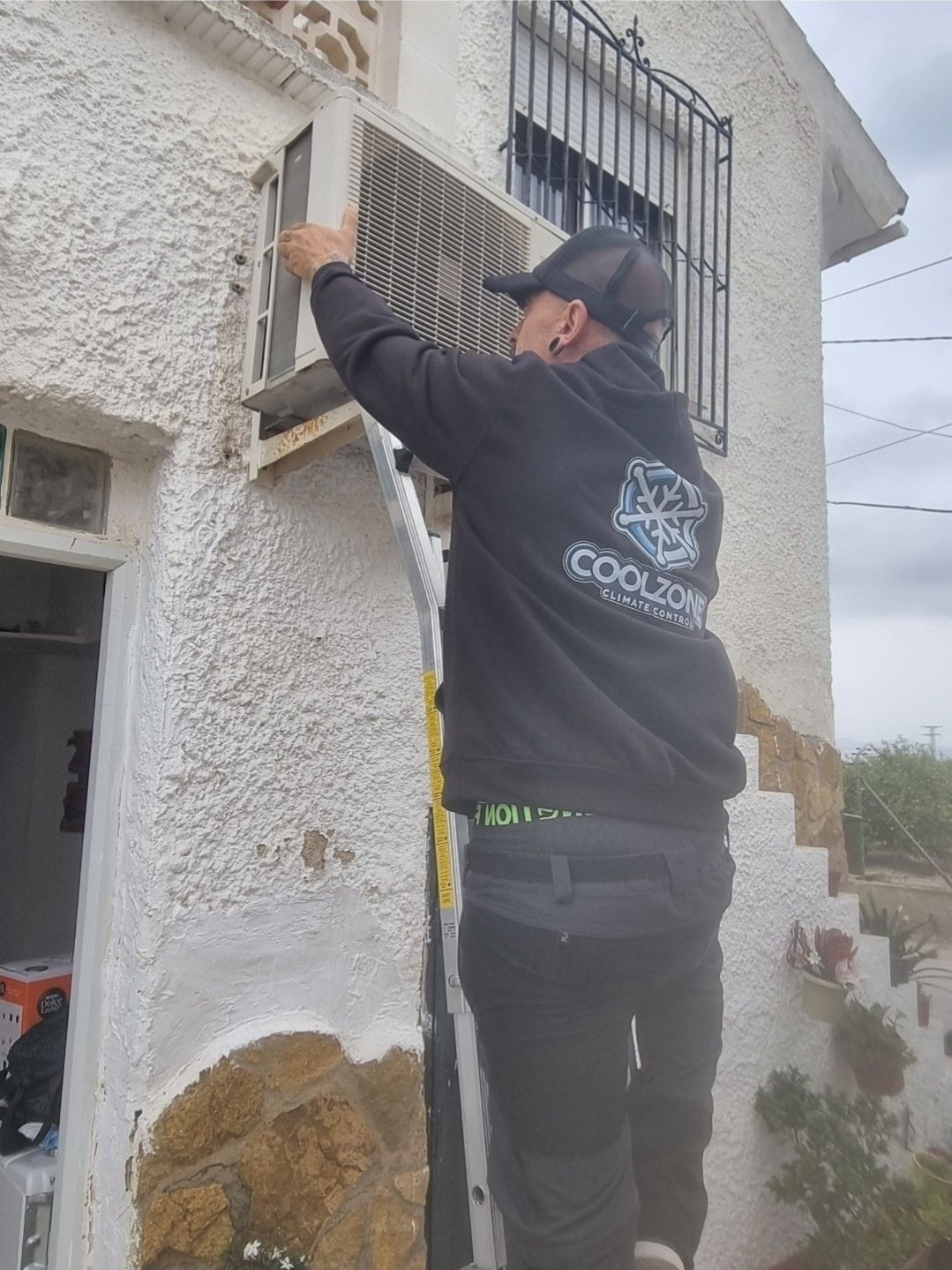 Técnico de CoolZone instalando unidad exterior en fachada